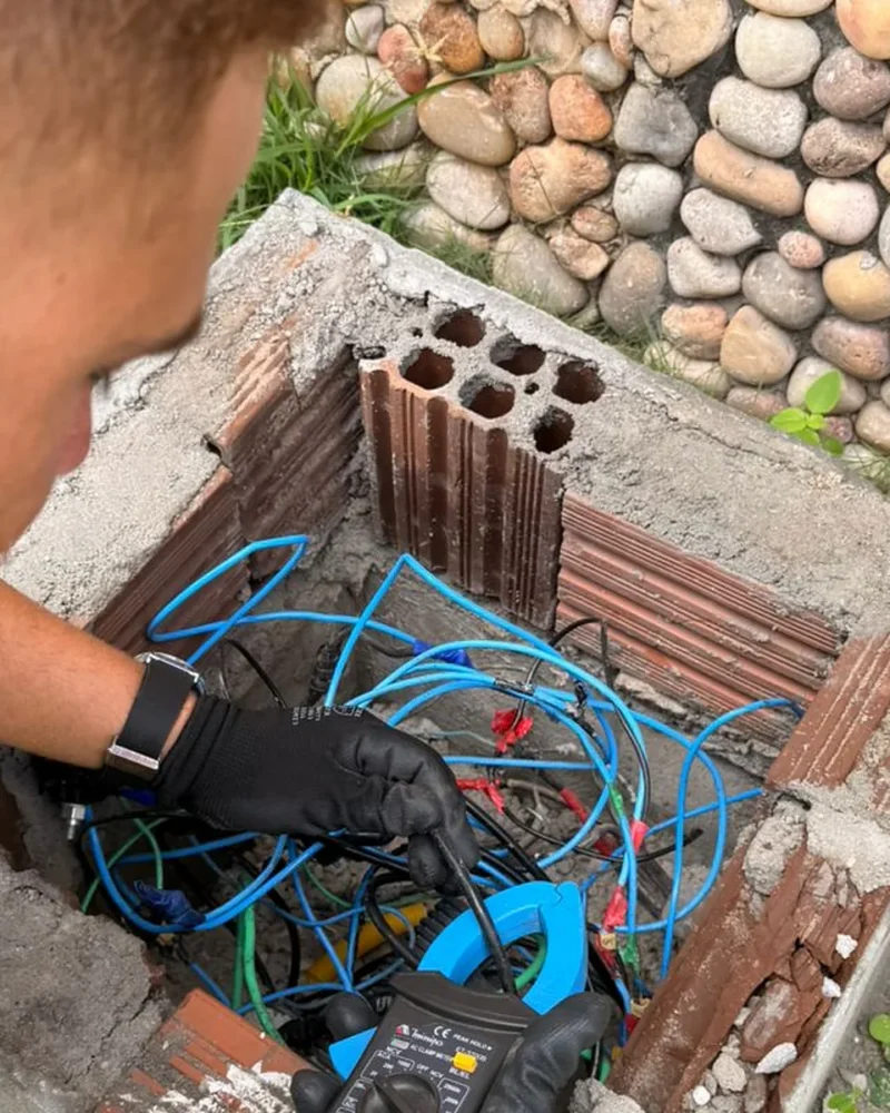 Técnico da Eletroserv e representante de concessionária de energia analisam juntos um quadro de distribuição elétrica aberto em ambiente interno.