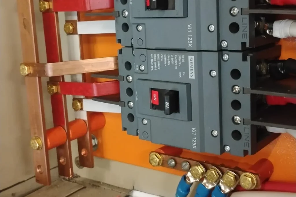 Quadro elétrico com dois disjuntores de 80A e dispositivos protetores de surto instalados sobre barramento laranja.